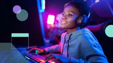Persona sonriendo mientras juega en computadora con auriculares.