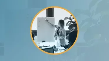 Mujer presentando en una pizarra durante una reunión de trabajo.
