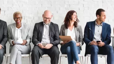Grupo de personas sentadas en una sala de espera.