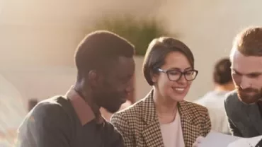 Personas trabajando juntas en una oficina, revisando documentos.