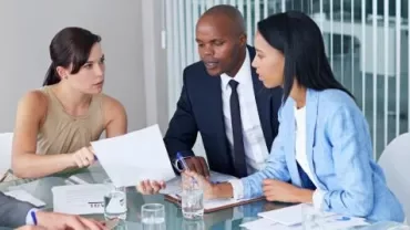 cuatro personas charlando en una mesa de trabajo
