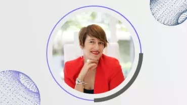 Persona sonriendo con chaqueta roja, fondo desenfocado.