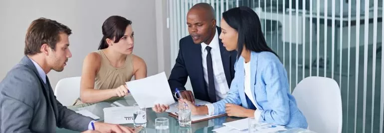 cuatro personas charlando en una mesa de trabajo