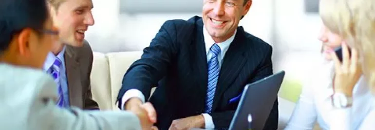 Grupo de personas en una reunión de negocios, estrechando las manos y sonriendo.