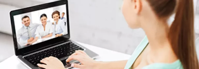 Persona en videollamada usando laptop en escritorio.