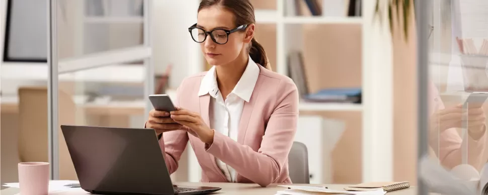 Mujer trabajadora revisando su móvil en una oficina.