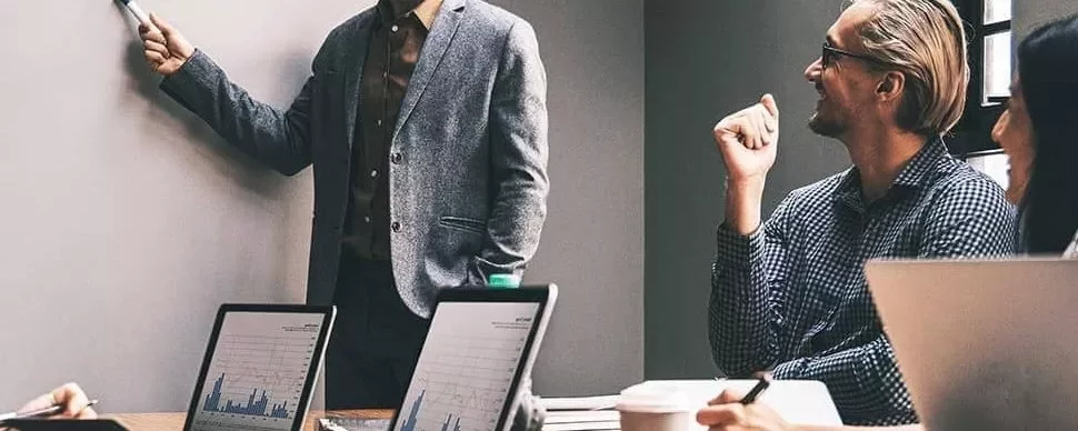 Personas en una reunión de trabajo con laptops y gráficos.