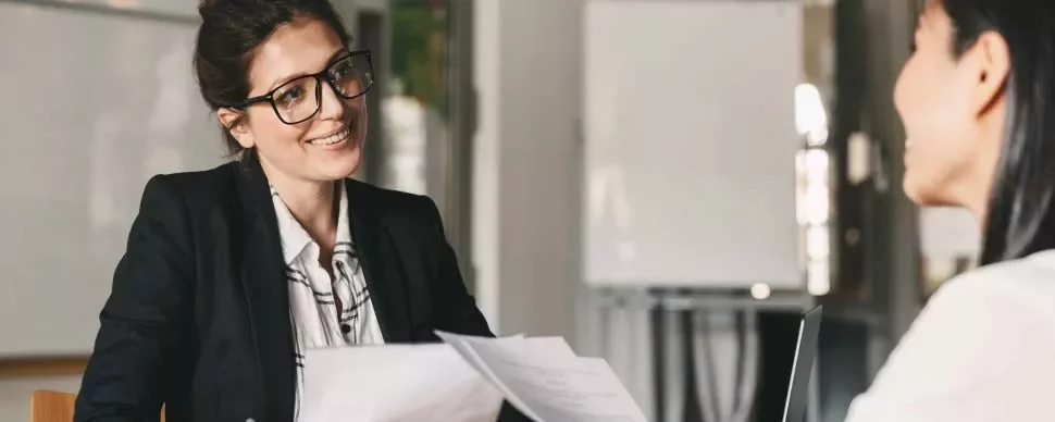 Entrevista laboral con dos mujeres conversando en una oficina.