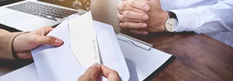Persona abriendo un sobre en una mesa de oficina.