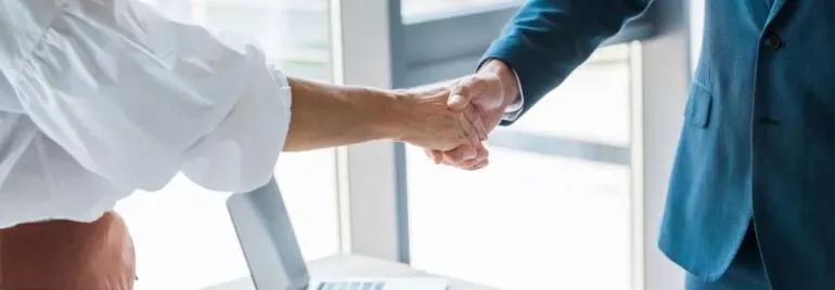 Dos personas dándose la mano en una oficina.