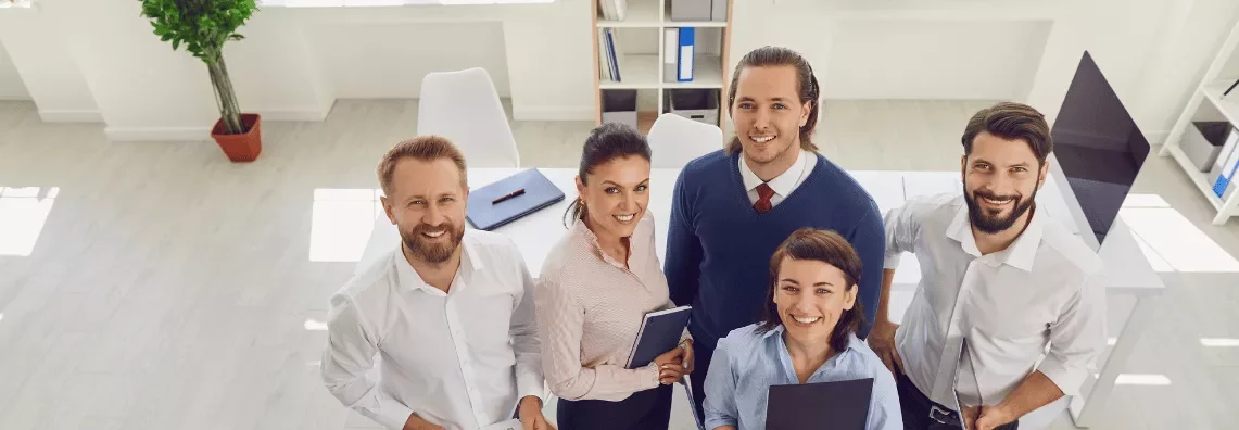 Grupo de personas en una oficina luminosa, sonriendo a la cámara.