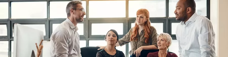 Personas en una reunión de trabajo discutiendo ideas frente a una ventana.