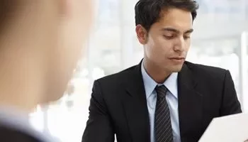 Hombre en traje observando un documento en una oficina.