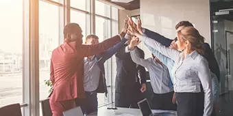 Grupo de personas en una oficina haciendo un choque de manos.