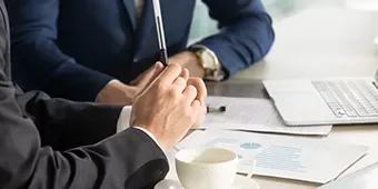 Personas en reunión de negocios con documentos y laptop.