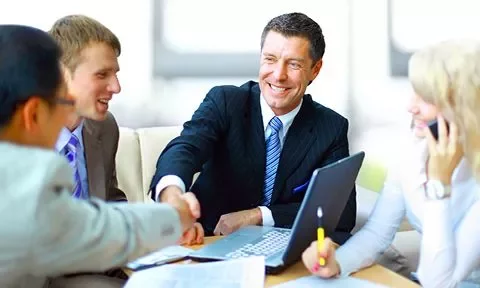 Grupo de personas en una reunión de negocios, estrechando las manos y sonriendo.