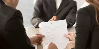 Entrevista de trabajo con personas trajeadas revisando un currículum.