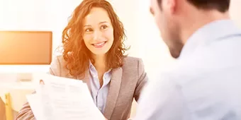 Mujer sonriente sosteniendo documentos en una reunión.