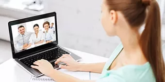 Persona en videollamada usando laptop en escritorio.