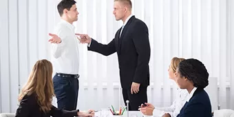 Dos hombres discutiendo en una reunión de oficina.